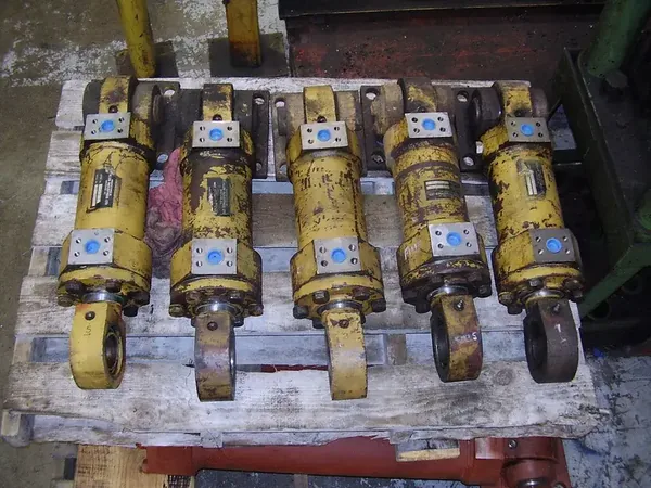 Row of yellow heavy equipment hydraulic cylinders waiting for repair
