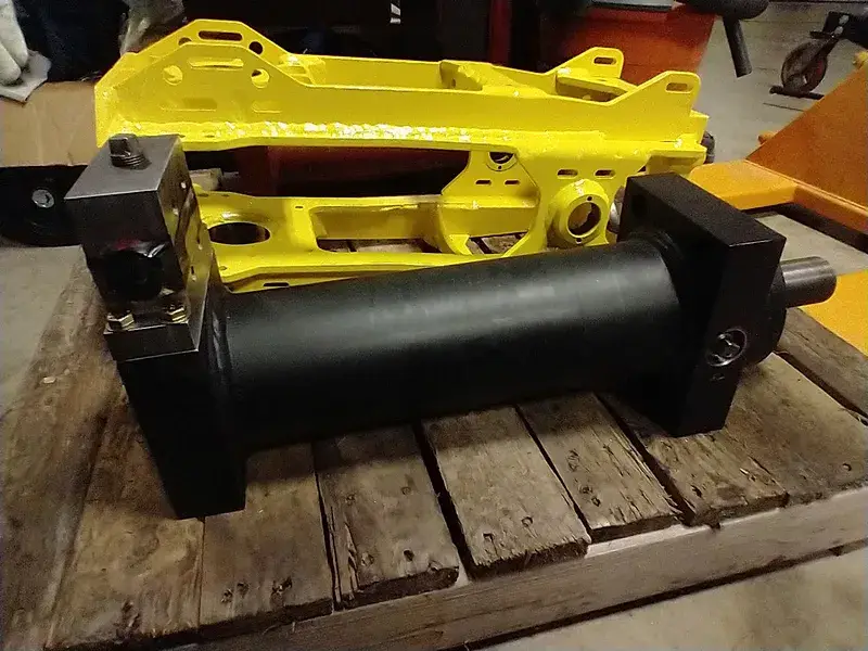 Yellow equipment component and hydraulic cylinder on the shop bench